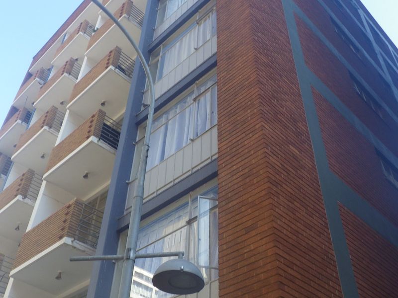 A low-angle view of a multi-story apartment building featuring a brick facade and a series of private balconies with metal railings.