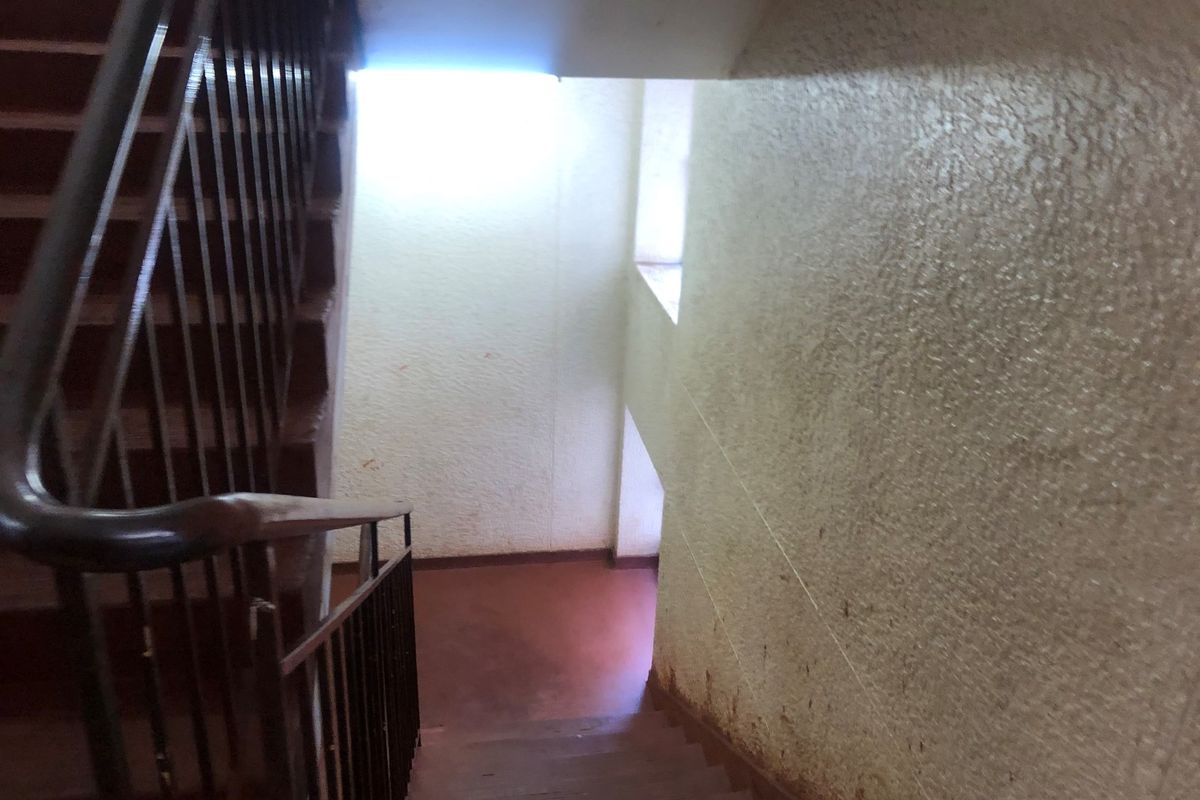 A communal stairwell featuring a metal balustrade and textured walls, showing signs of wear and requiring maintenance or cosmetic updates.