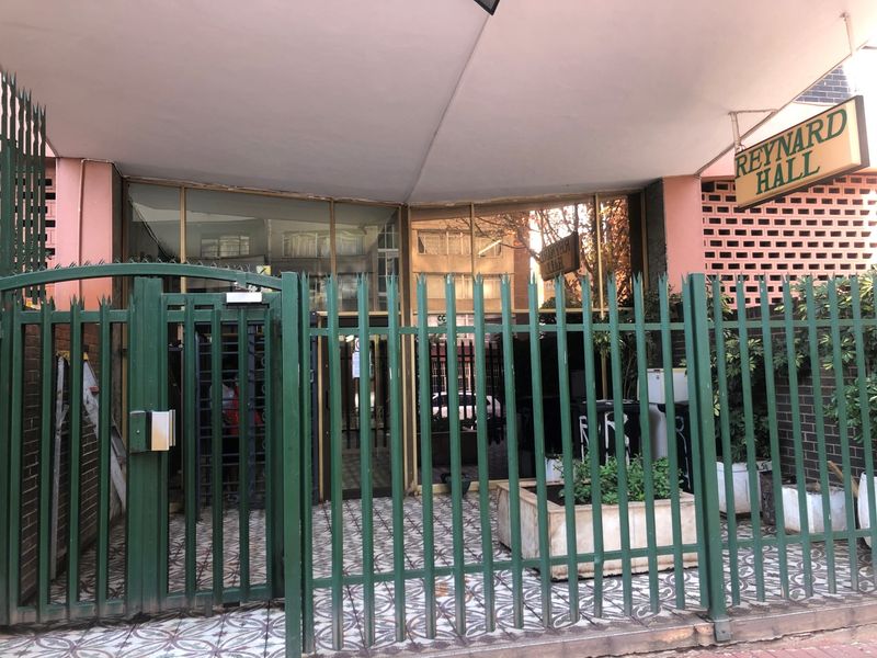 Front entrance of Reynard Hall featuring a secure metal gate, glass facade, and brick exterior detailing.