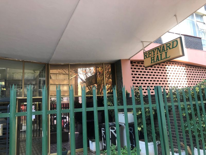 The front entrance of Reynard Hall, featuring a covered walkway, secure metal fencing, and brick facade detailing.
