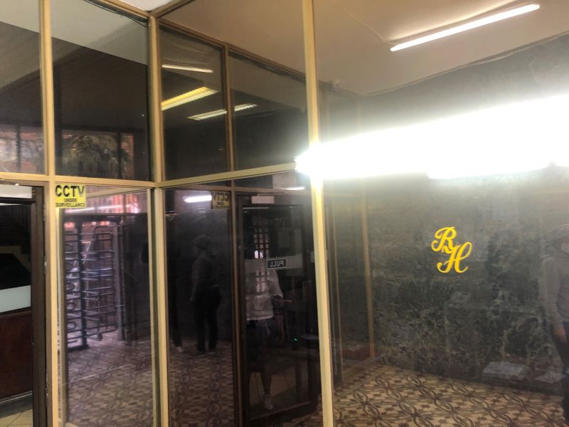 The building entrance features a glass-partitioned lobby with a stone feature wall, patterned flooring, and fluorescent lighting.
