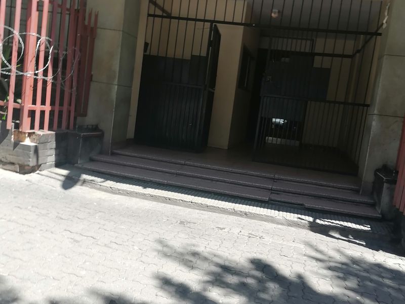 Front entrance of Hyde Park Corner apartment complex featuring a secure gated access point and paved driveway area.