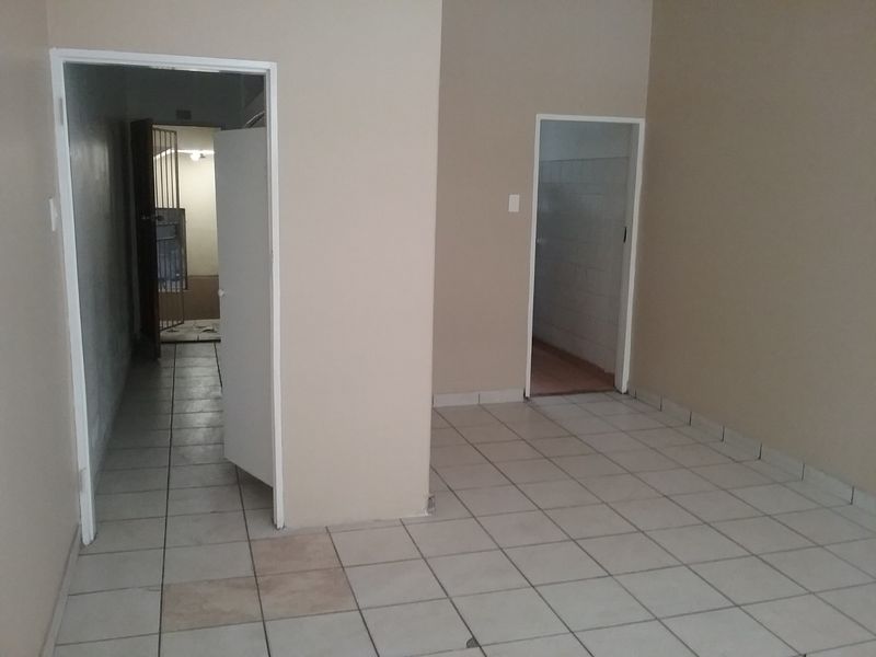 An empty interior hallway featuring ceramic tiled flooring and access to multiple rooms, including a secure gated area.