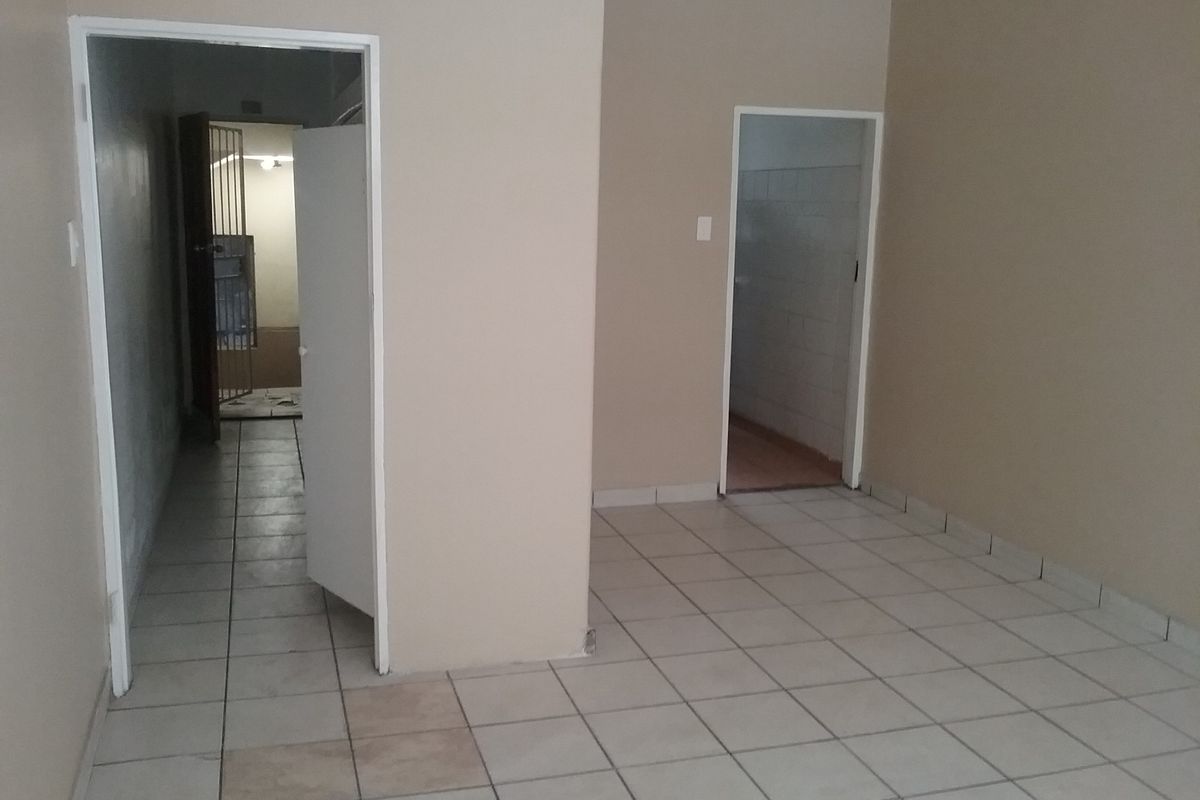 An empty interior hallway featuring ceramic tiled flooring and access to multiple rooms, including a secure gated area.