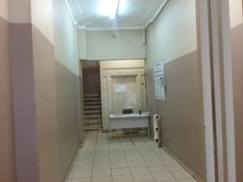 Commercial building entrance lobby featuring tiled flooring, decorative ceiling molding, and access to an internal staircase.