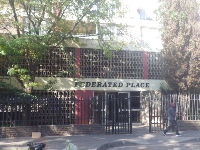 Front elevation of Federated Place apartment building featuring a distinctive decorative breeze block facade and secure gated pedestrian entrance.