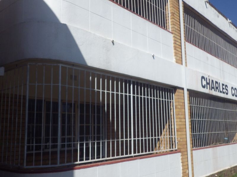 Exterior view of Charles Court apartment building featuring brick and plastered facade with installed security bars on windows.