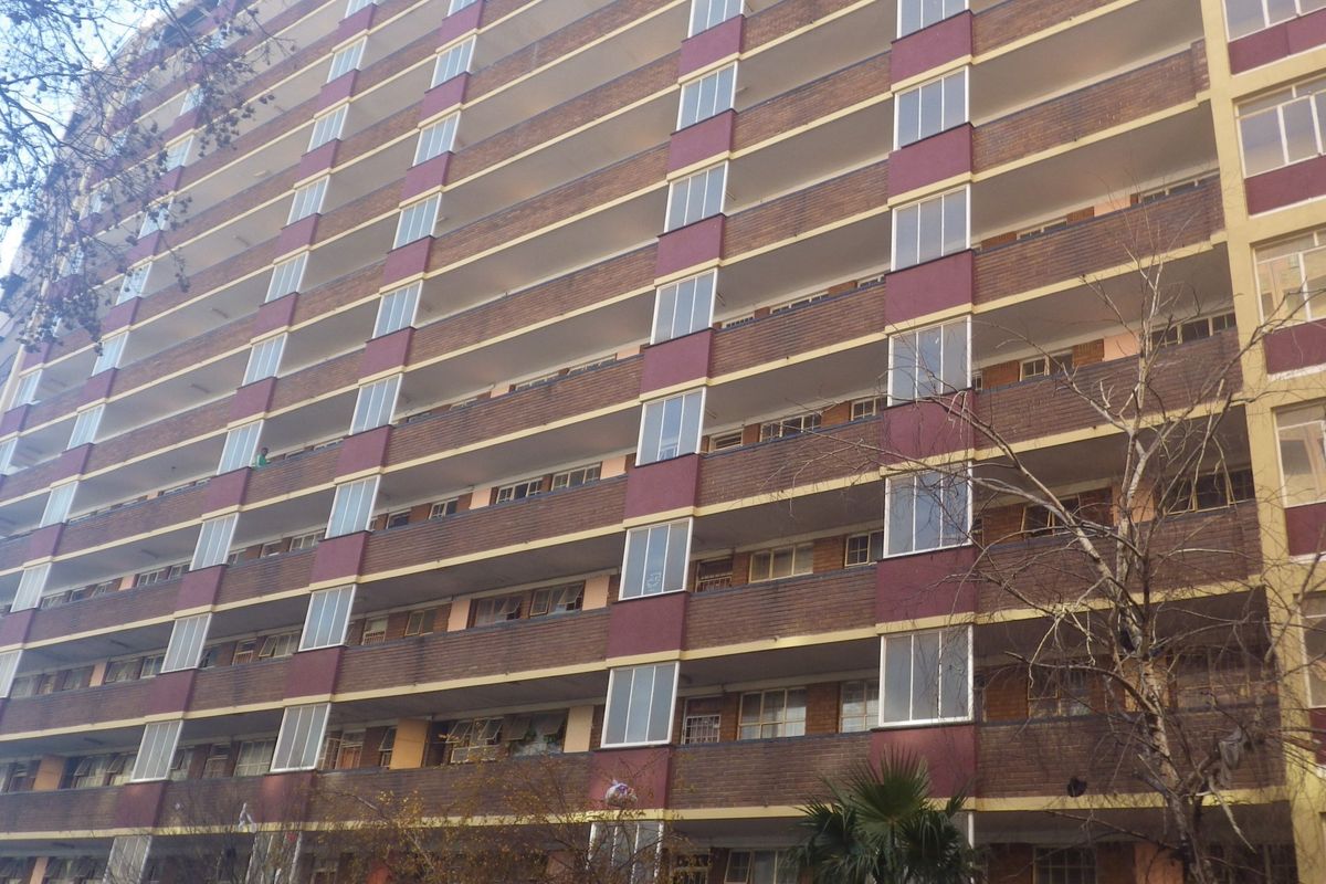 A multi-story residential apartment building featuring a brick facade with integrated balconies and large windows.