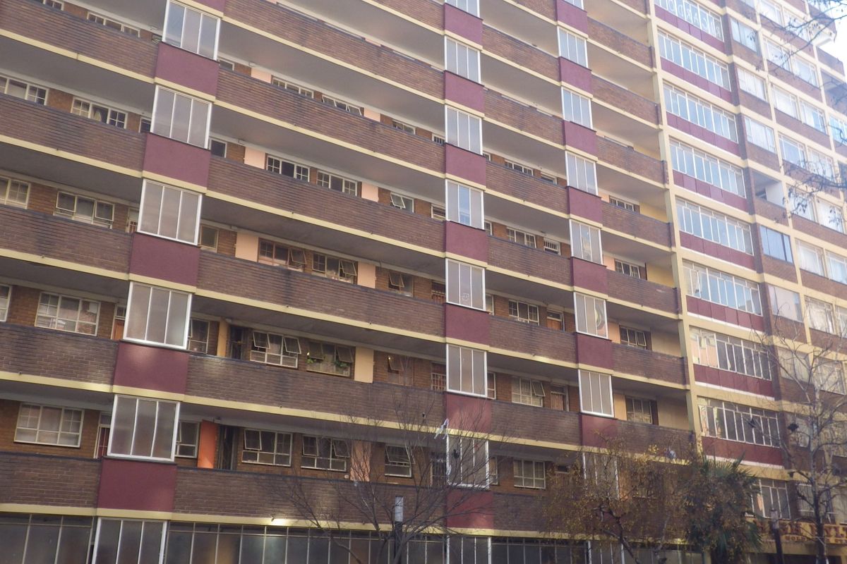 A multi-story residential apartment building featuring a brick facade with integrated balconies and aluminium window frames.