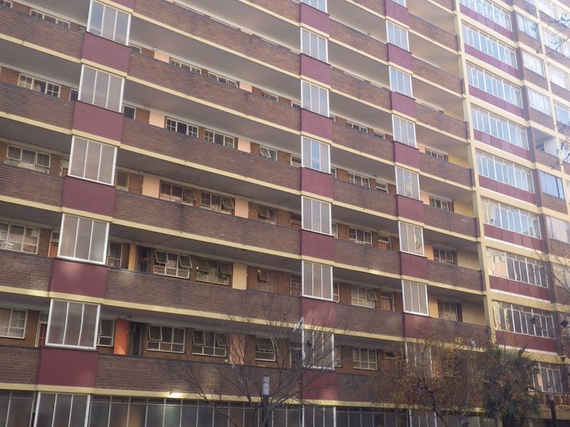 A multi-story residential apartment building featuring a brick facade with integrated balconies and aluminium window frames.