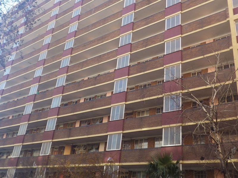 A multi-story residential apartment building featuring a brick facade with integrated balconies and large windows.