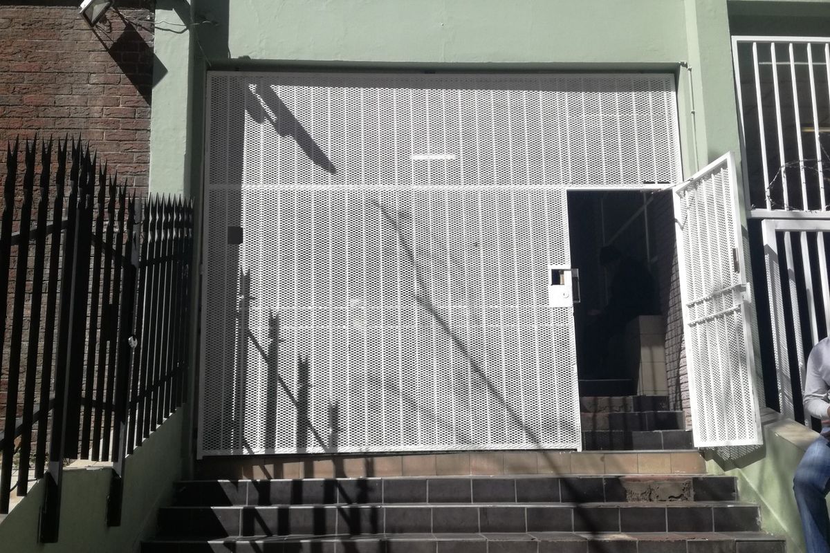 Front entrance of the Tygerberg building featuring a security gate, tiled staircase, and brick facade.