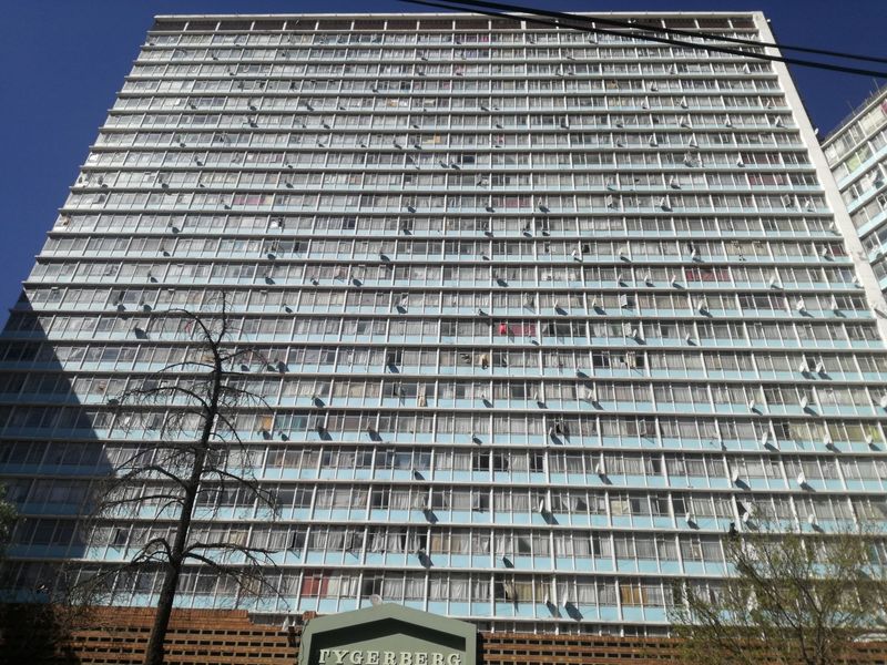 A low-angle view of the Tygerberg high-rise apartment building, showcasing its multi-story facade with numerous windows and balcony structures.
