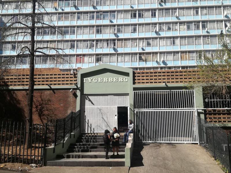 Front entrance view of the Tygerberg apartment complex, featuring a secure gated driveway, concrete staircase, and multi-story residential facade.
