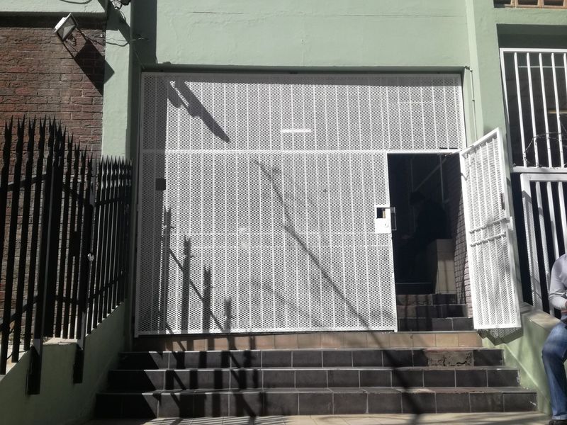 Front entrance of the Tygerberg building featuring a security gate, tiled staircase, and brick facade.