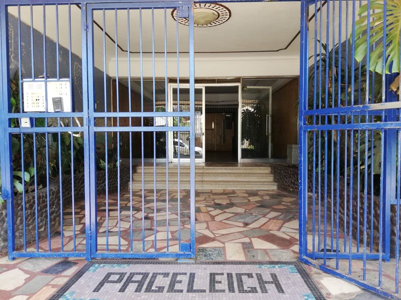 The entrance to Paceleigh features a secure gated access point with mosaic flooring, stone cladding, and a glass-doored lobby area.