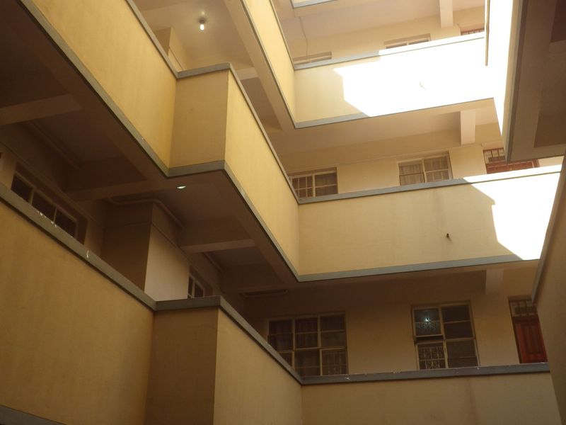 View of the apartment building's central courtyard and stairwell structure, showing multi-level access balconies and exterior facade.