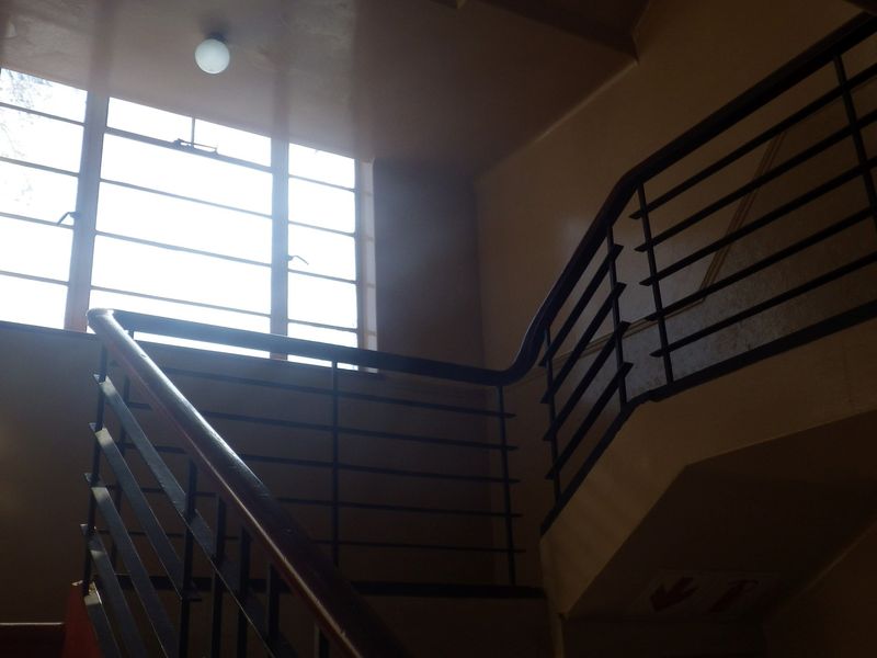 A view of an interior stairwell featuring a metal railing and a large multi-pane window providing natural light.