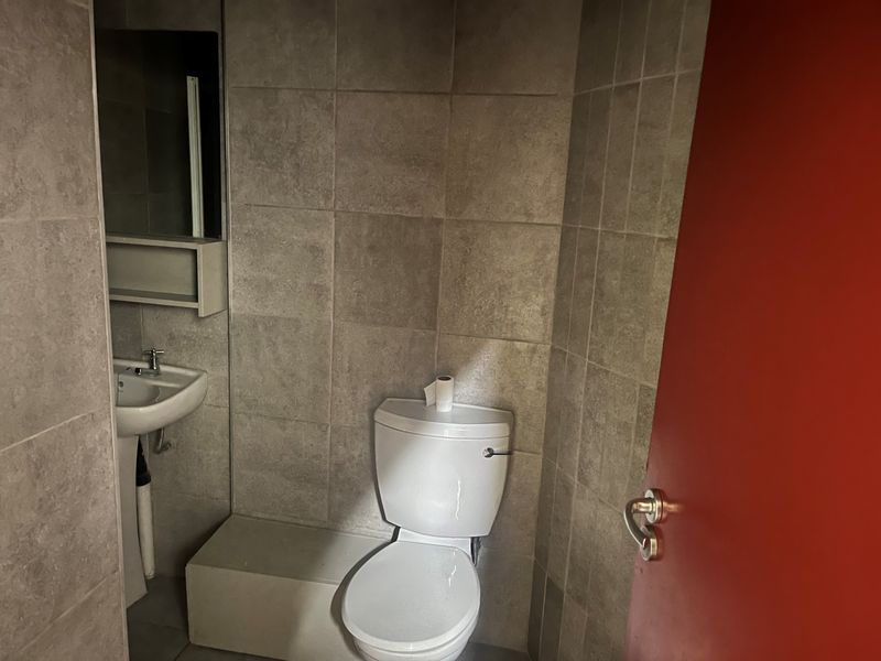 A compact bathroom featuring tiled walls and flooring, a pedestal basin, and a standard toilet.