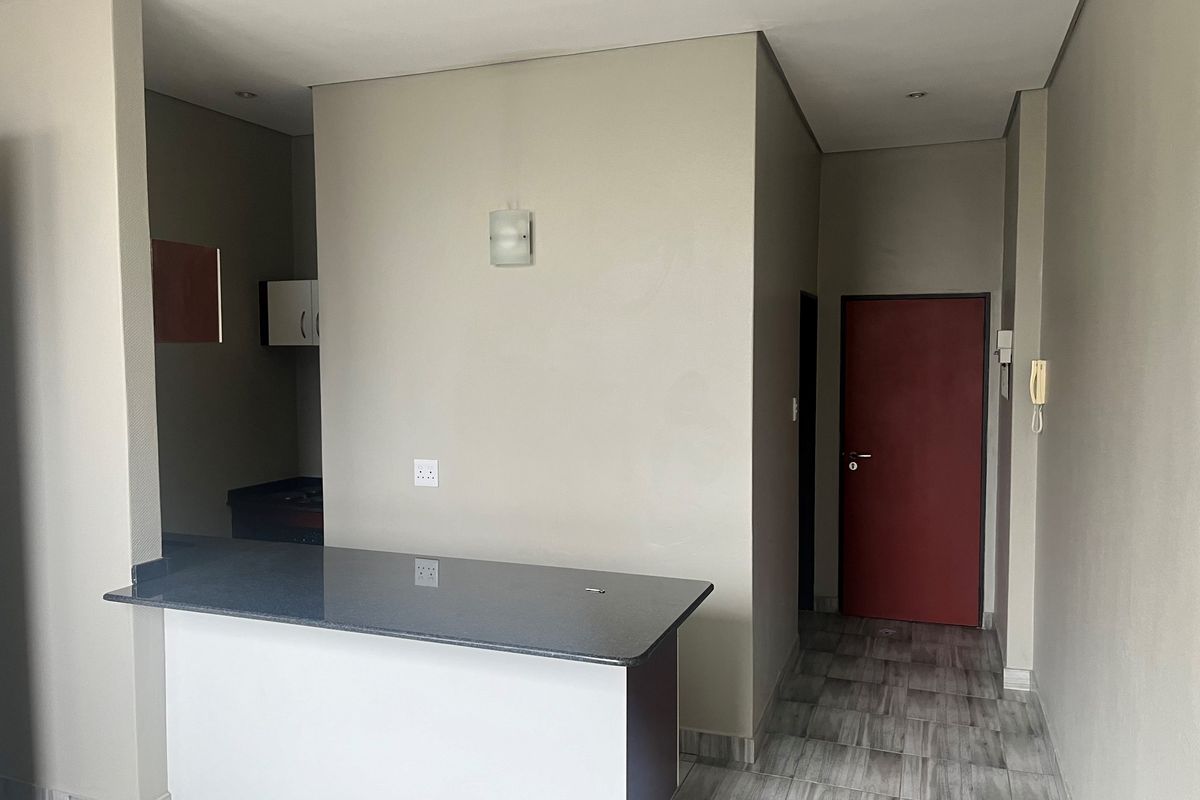 An open-plan living area featuring a granite breakfast counter, tiled flooring, and neutral wall finishes, providing a clean and functional space.