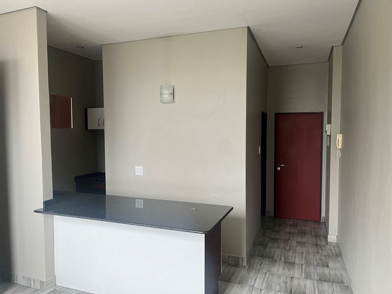 An open-plan living area featuring a granite breakfast counter, tiled flooring, and neutral wall finishes, providing a clean and functional space.