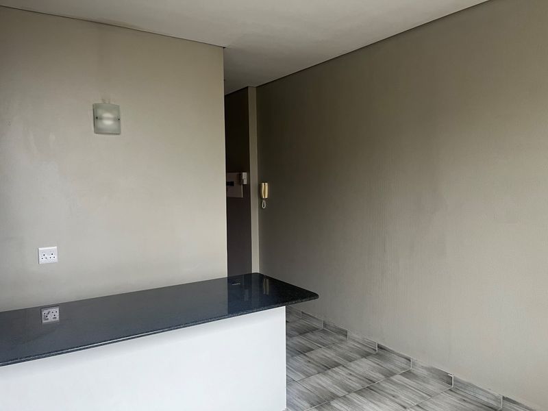 An open-plan area featuring a granite breakfast bar, neutral wall finishes, tiled flooring, and a wall-mounted intercom system.