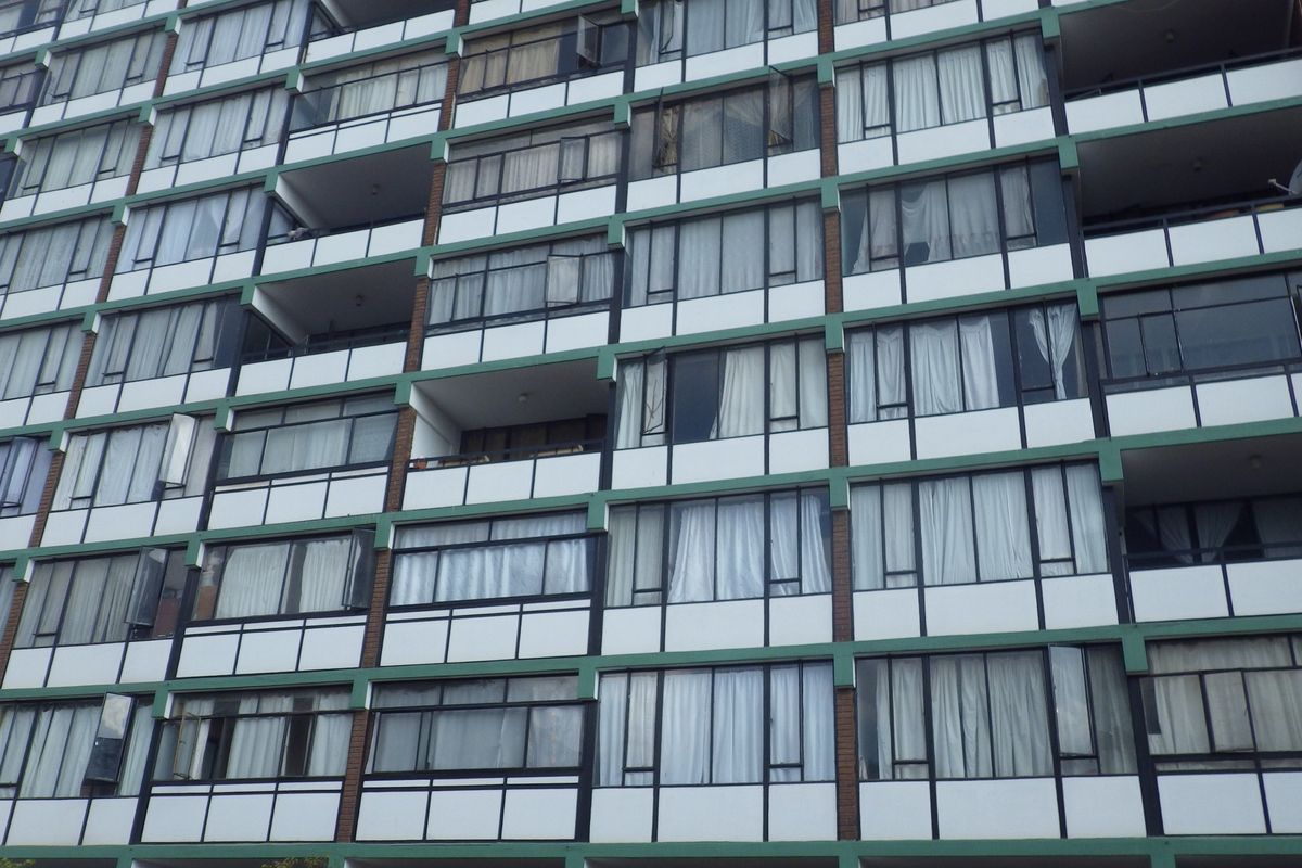 A multi-story apartment building facade featuring rows of balconies and large windows with a classic architectural design.