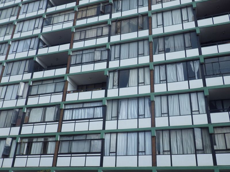 A multi-story apartment building facade featuring rows of balconies and large windows with a classic architectural design.
