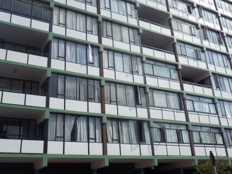 A multi-story apartment building facade featuring rows of balconies with large windows and sliding doors, showcasing a classic mid-century architectural style.