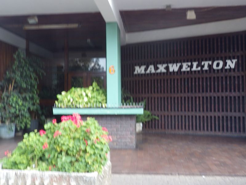The entrance facade of Maxwelton apartment building, featuring a covered entryway with timber slat detailing and a masonry planter box.
