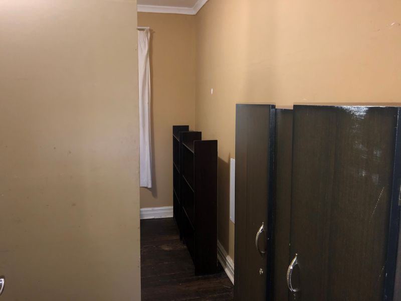 A bedroom space featuring dark timber flooring and neutral wall tones, requiring minor cosmetic updates to refresh the interior finishes.