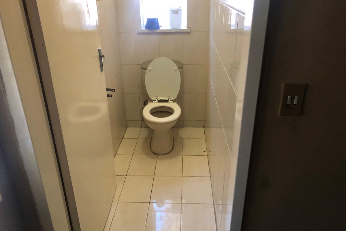 A compact, functional bathroom featuring tiled walls and flooring with a standard toilet fixture.