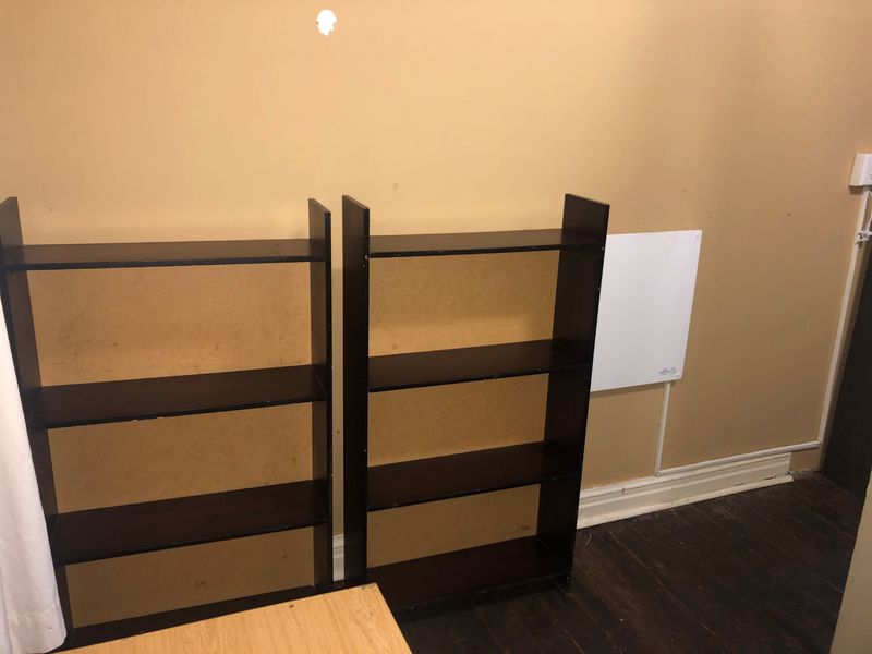 Interior space featuring dark timber flooring and a wall-mounted electric heater, showing signs of wear on the walls and floor.