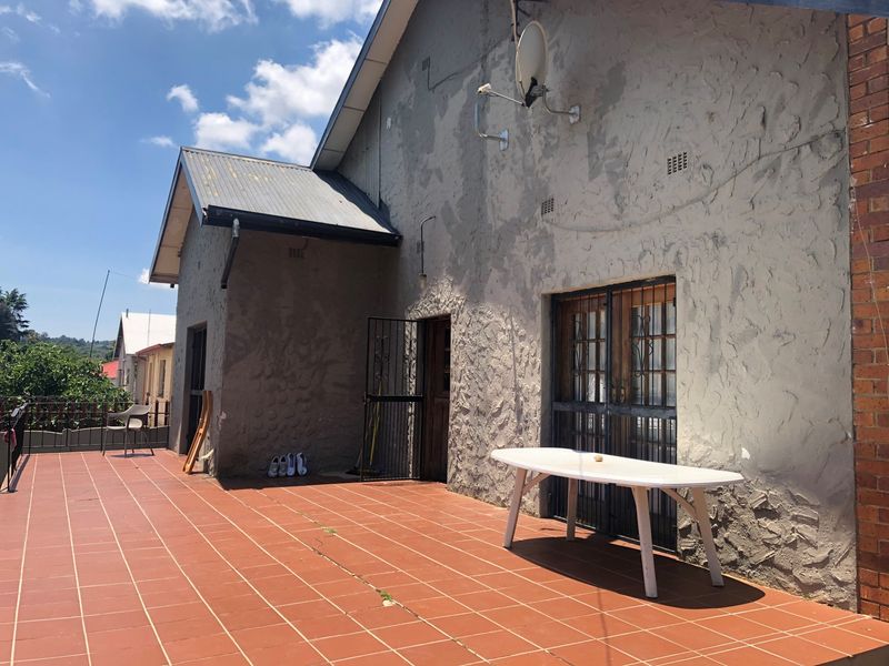 Spacious outdoor patio area featuring tiled flooring and metal security gates, providing access to the main dwelling with a weathered exterior finish.
