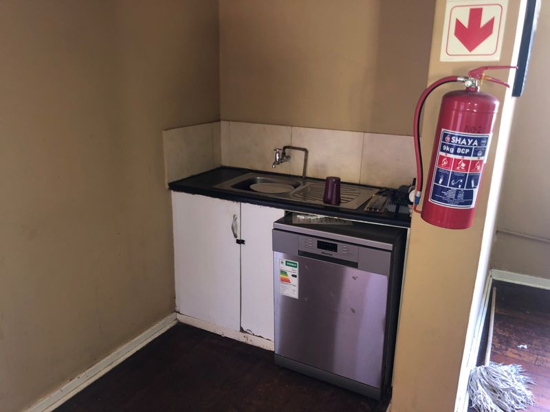 A compact scullery area featuring a stainless steel sink, tiled splashback, and built-in cabinetry, providing essential utility space.