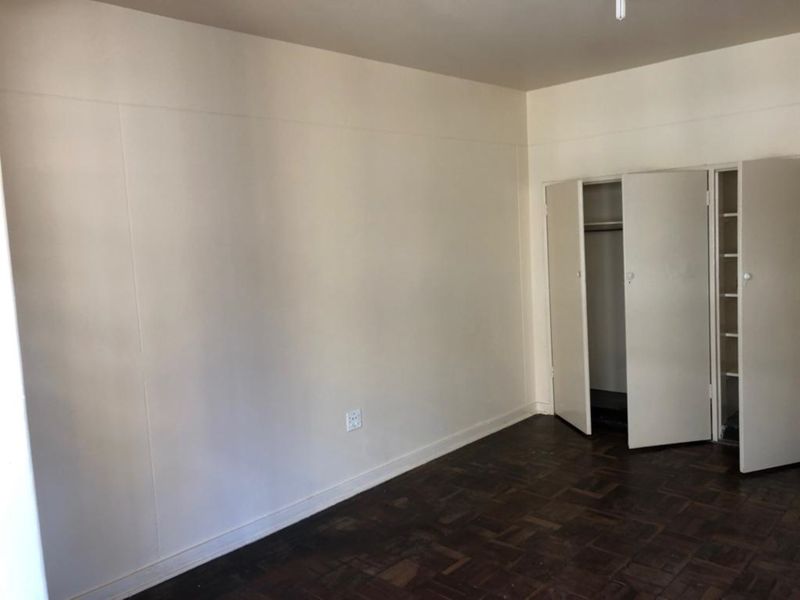 A vacant bedroom featuring original parquet flooring and a built-in wardrobe with double doors.
