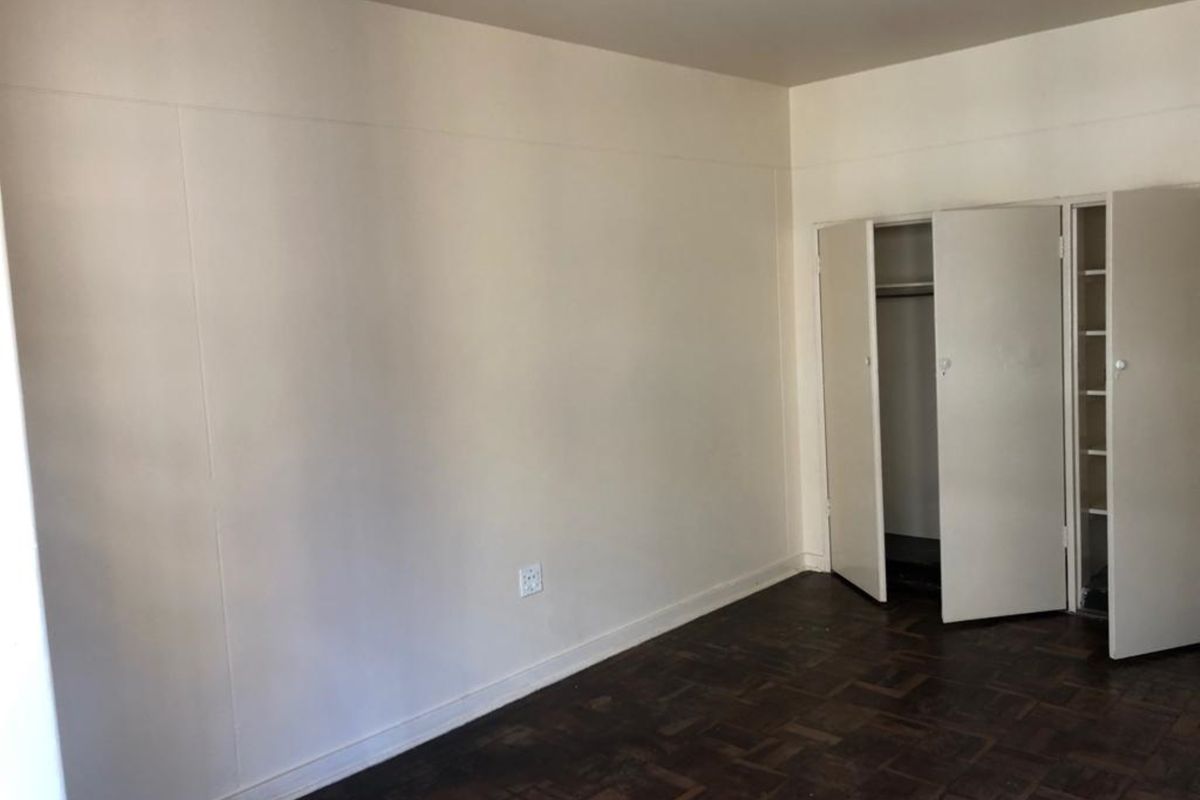 A vacant bedroom featuring original parquet flooring and a built-in wardrobe with double doors.