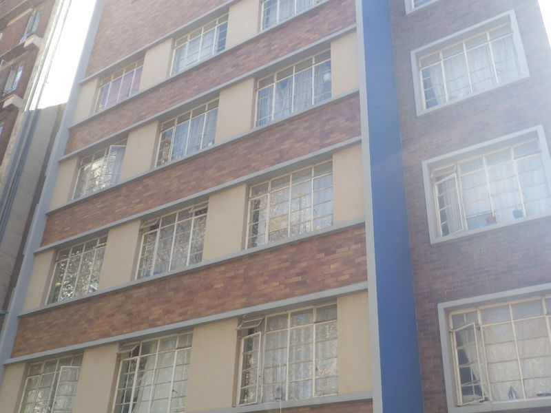A multi-story residential building facade featuring classic brickwork and multiple steel-framed windows.