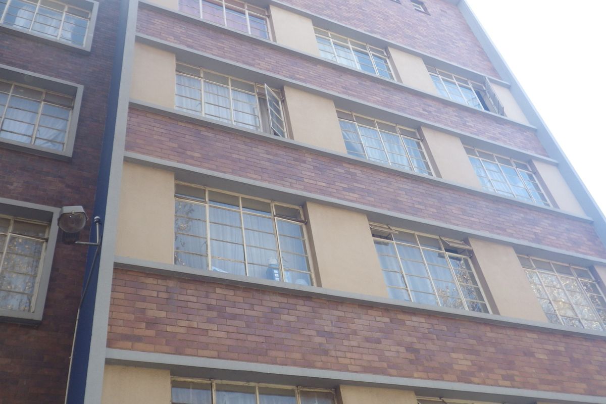 A view of the multi-story brick facade featuring classic multi-pane steel windows and exterior wall-mounted lighting.