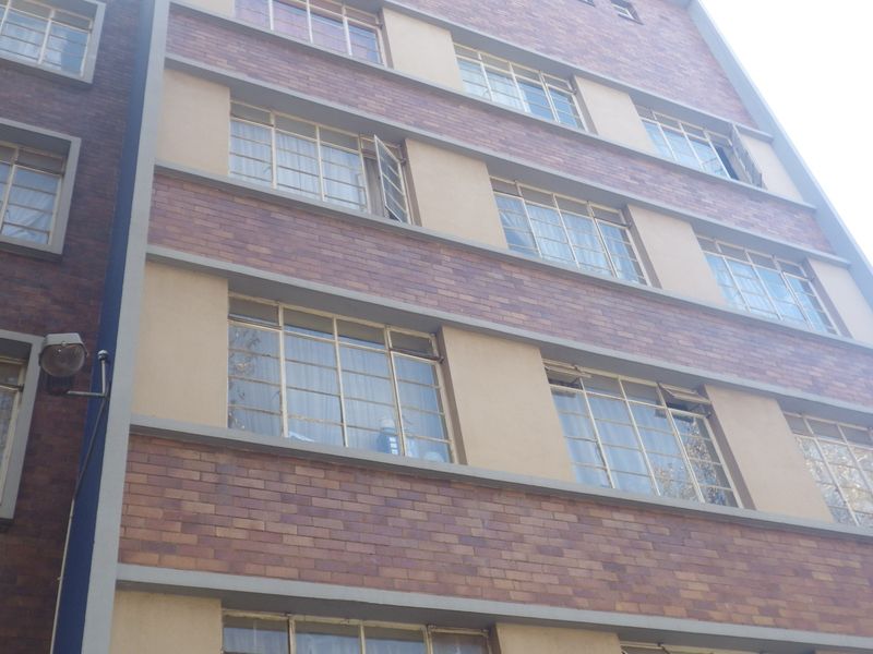 A view of the multi-story brick facade featuring classic multi-pane steel windows and exterior wall-mounted lighting.