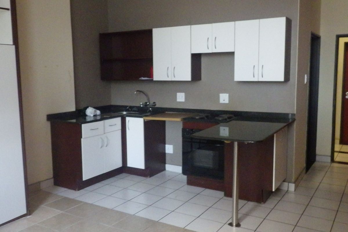 A compact kitchen featuring two-tone cabinetry, dark granite countertops, a built-in oven, and tiled flooring.
