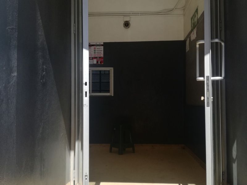 A functional entrance area featuring double glass doors, security cameras, and neutral wall finishes, providing a secure access point to the property.