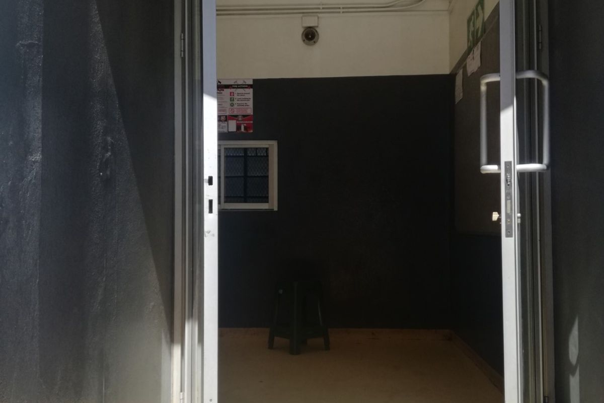 A functional entrance area featuring double glass doors, security cameras, and neutral wall finishes, providing a secure access point to the property.