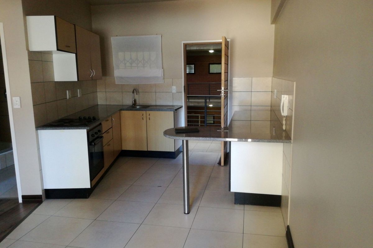 A functional kitchen featuring built-in cabinetry, granite countertops, a breakfast bar, and tiled flooring, offering a clean and practical layout.
