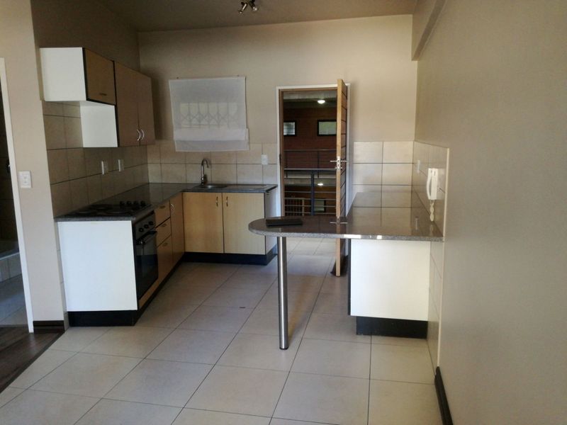 A functional kitchen featuring built-in cabinetry, granite countertops, a breakfast bar, and tiled flooring, offering a clean and practical layout.