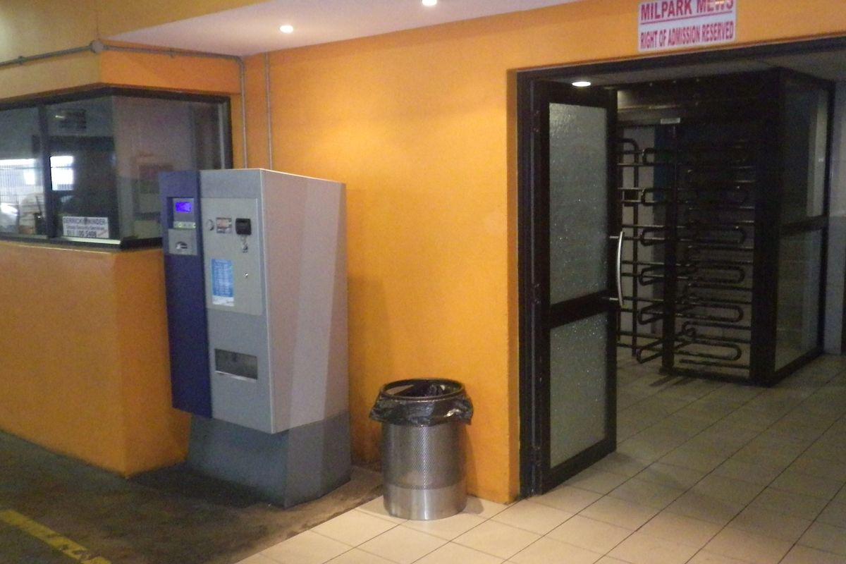 Building entrance area featuring a security turnstile, glass door access, and a dedicated security booth with tiled flooring.