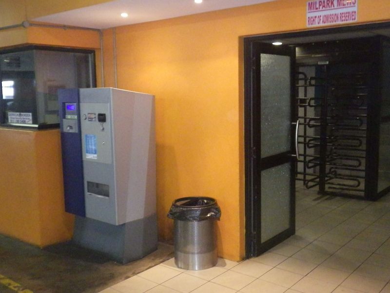 Building entrance area featuring a security turnstile, glass door access, and a dedicated security booth with tiled flooring.
