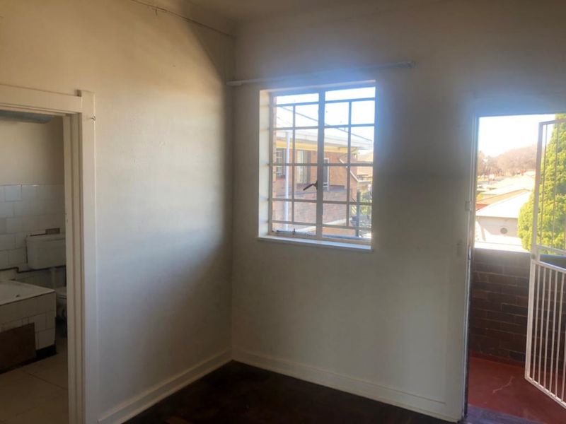 An empty bedroom featuring security bars on the window and direct access to an adjoining bathroom.