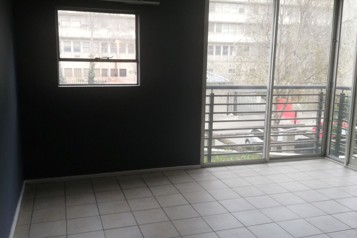 An empty living area featuring tiled flooring, dark accent walls, and large sliding glass doors leading to a balcony.